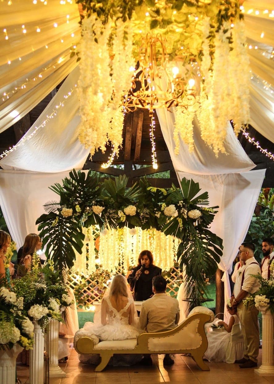 Ceremonia de noche bajo un techo de luces, telas y flores blancas