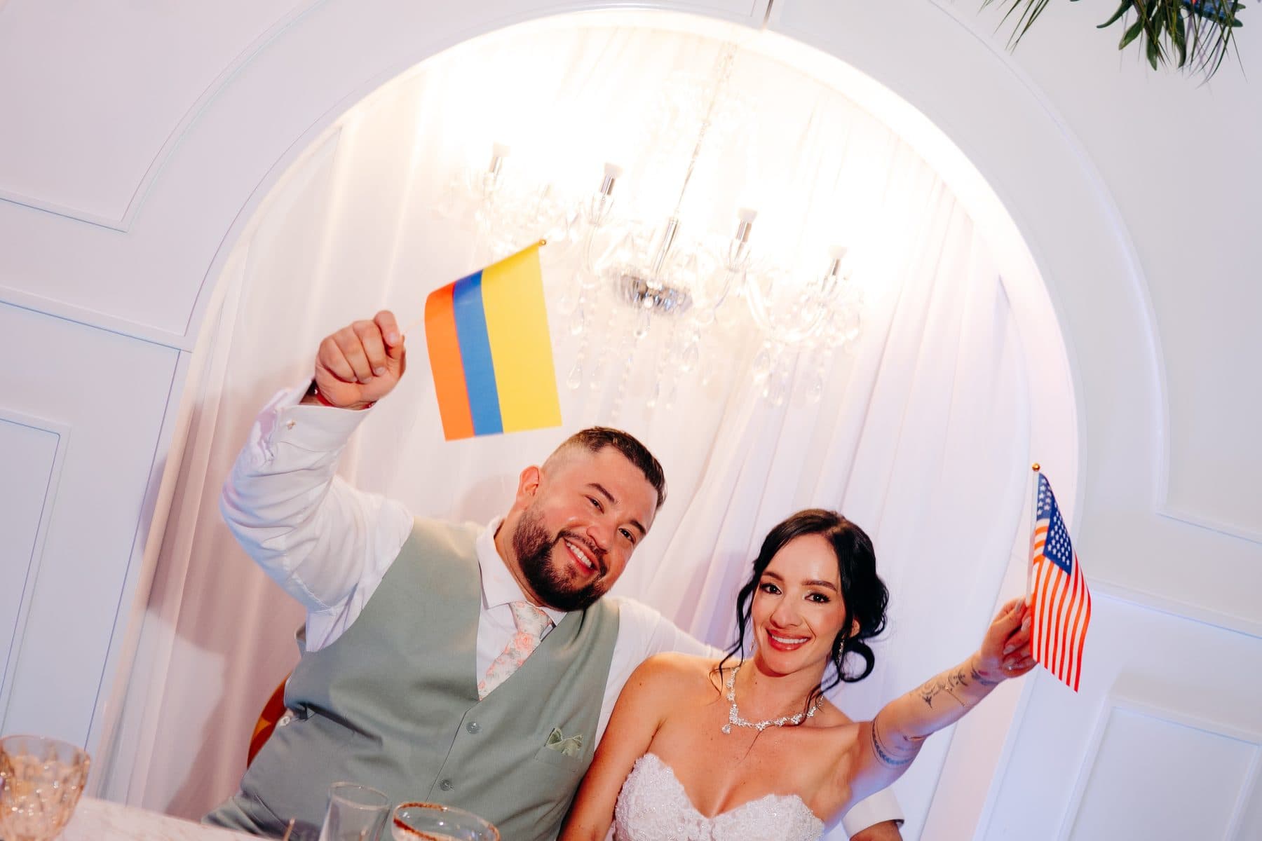 The couple raises the flags of Colombia and the United States at their head table