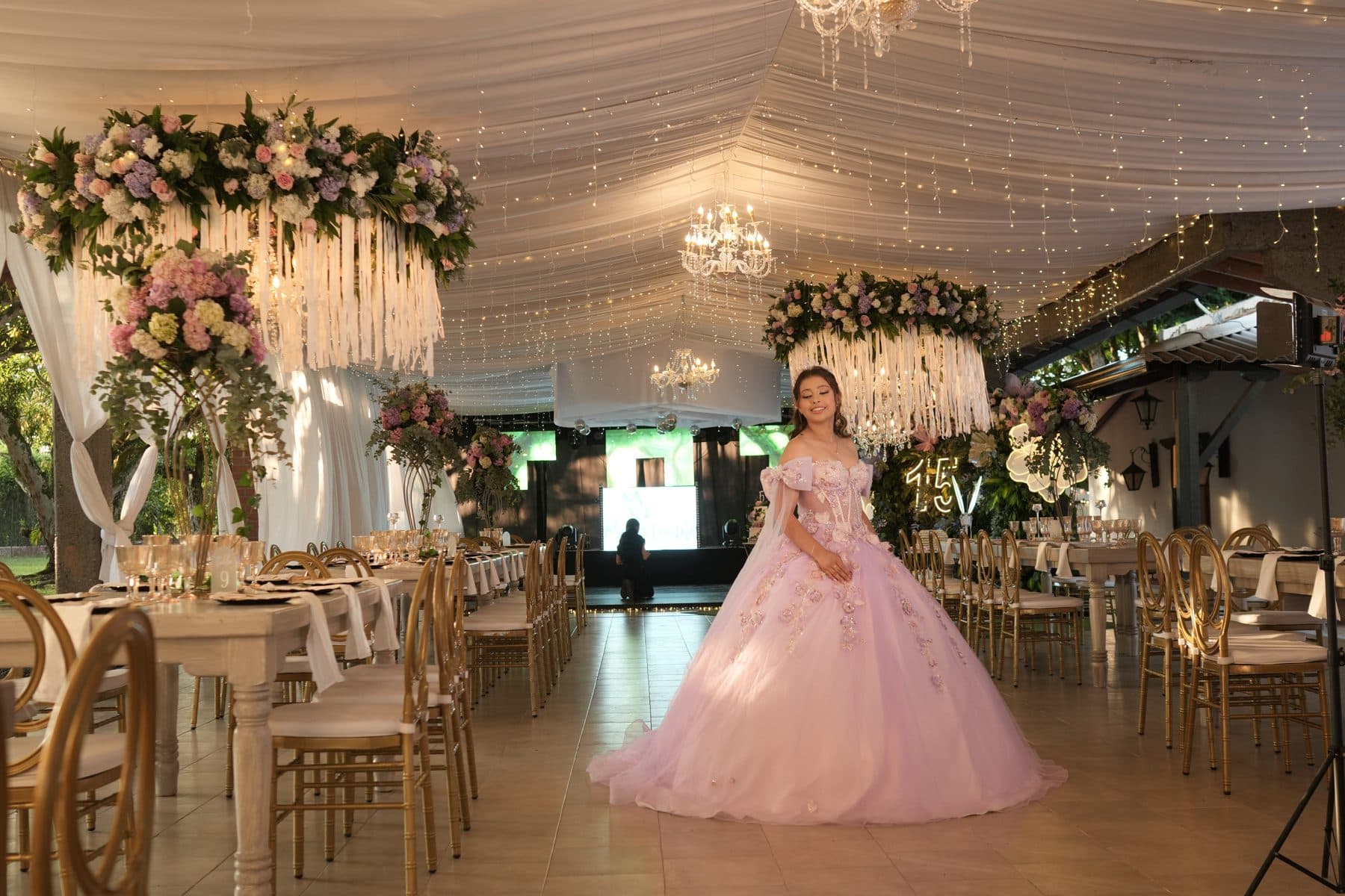 Quinceañera in a ballroom with crystal chandeliers and a ceiling of lights