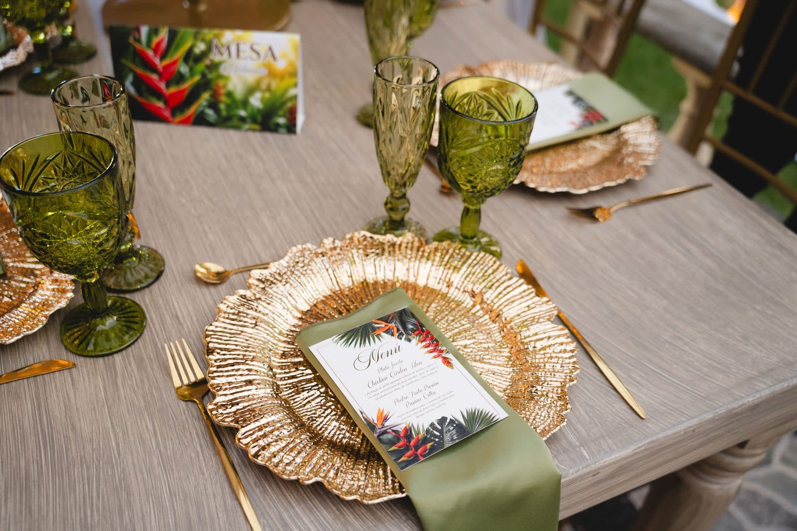 Place setting with a gold charger, menu card and green glasses