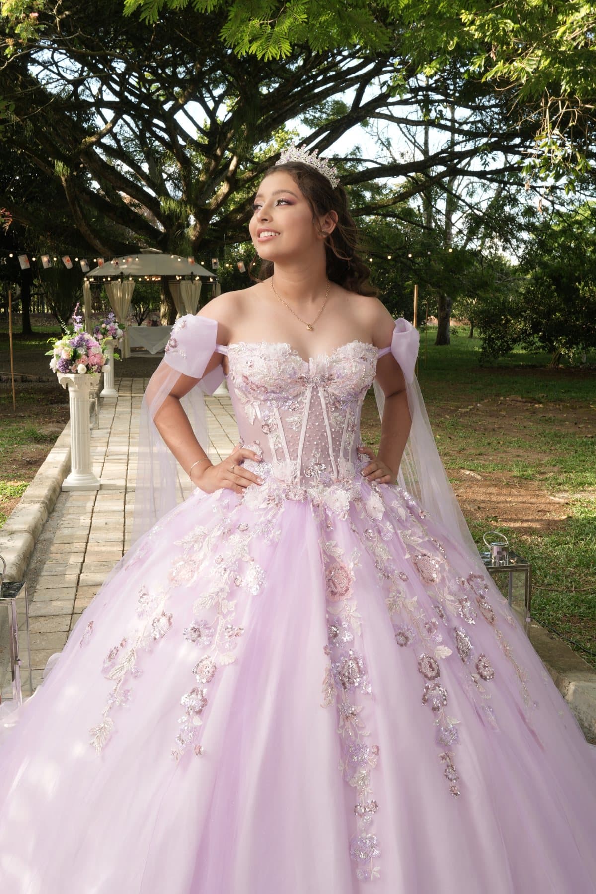 María Camila con vestido rosa en un jardín, junto a una glorieta