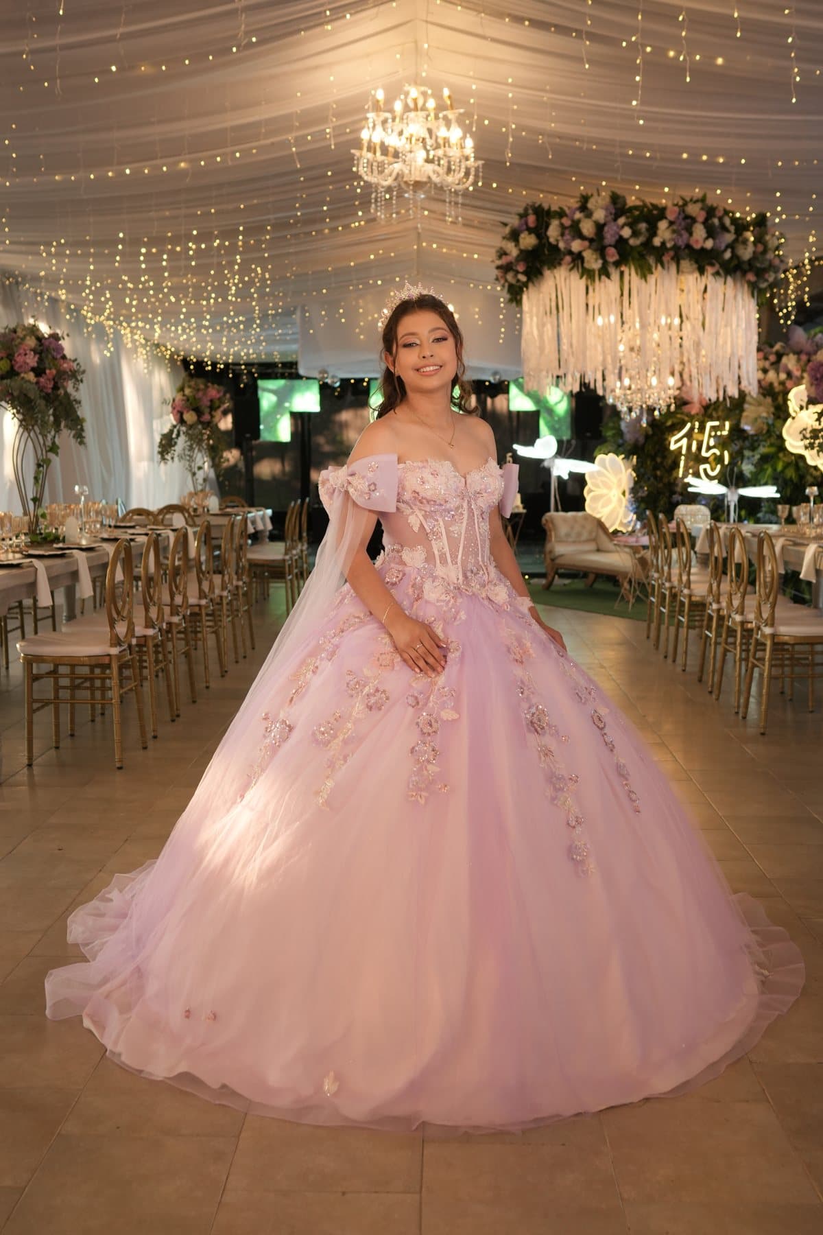 María Camila en el salón bajo lámparas de cristal y flores colgantes